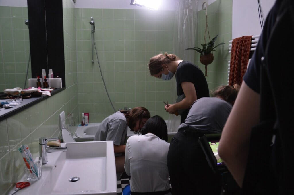 Foto von mehreren Menschen, die um die Hauptdarstellerin des Kulmine-Image-Filmes stehen, während diese für den Film auf der Toilette sitzt.
